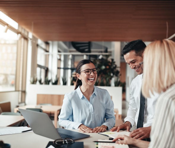 Businesspeople laughing while working at an office table Businesspeople laughing while working at an office table